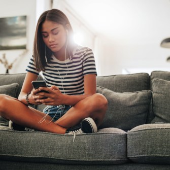 Teenage girl sitting on a couch at home.