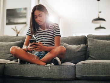 Teenage girl sitting on a couch at home.