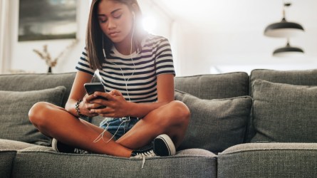 Teenage girl sitting on a couch at home.