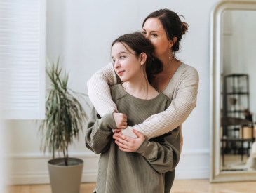 Portrait of mother middle age woman and daughter teenager together in light interior