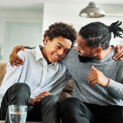 Portrait of a happy teenage boy son talking to his father at home. Sharing secrets and having fun, support and parenthood concept