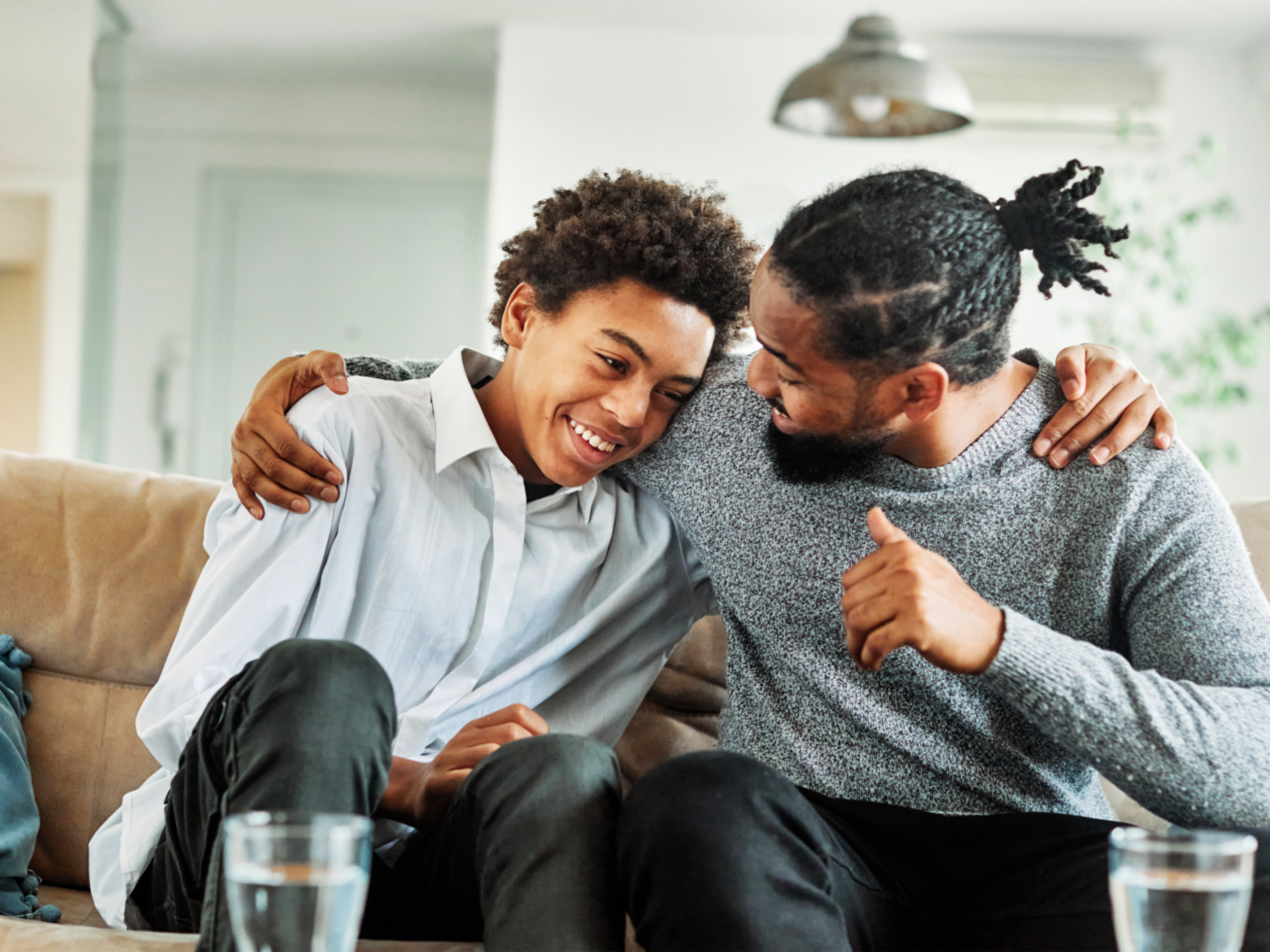 Portrait of a happy teenage boy son talking to his father at home. Sharing secrets and having fun, support and parenthood concept