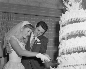 (Original Caption) 9/26/1955-Liberty, NY- Actress Debbie Reynolds and singer Eddie Fisher cut their towering wedding cake after they were married at Liberty, NY. Their much publicized romance came to a climax in the three minute ceremony at the home of Dr. and Mrs. David Etefs. It was at the Grossinger Resort that Fisher began his meteoric rise to fame a decade ago -- at $30 a week. He and Miss. Reynolds had originally planned to be married last June. When the wedding didn't take off, columnists speculated that the romance fizzled out.