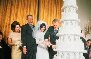 (Original Caption) Mr. and Mrs. Pat Nugent with their wedding cake at the White House as President and Mrs. Johnson look on during the reception following Luci's wedding, August 6th.