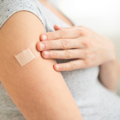 Vaccination of a pregnant woman. Close view of shoulder after vaccine injection with adhesive tape. Covid vaccination concept. Health and medicine during pregnancy.