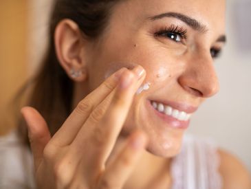 Woman rubbing moisturizer on her cheek